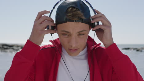 portrait of cool confident boy on beach puts on headphones listening to music