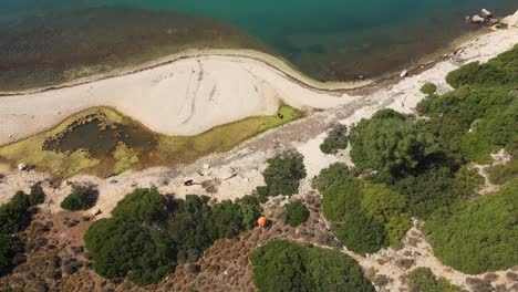 avión no tripulado volando sobre una playa remota e inaccesible al pie de una montaña con cabras salvajes vagando por la playa