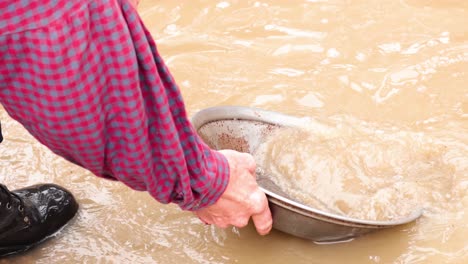 person panning for gold in muddy water