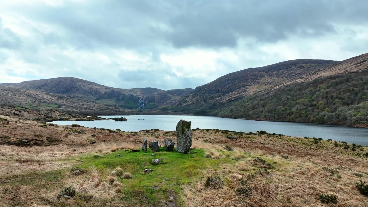 Droneflyvning over det vilde Irland med Uragh Stående Sten og det vilde landskab ved Gleninchquin Sø omgivet af bjerge i det episke Kerry.