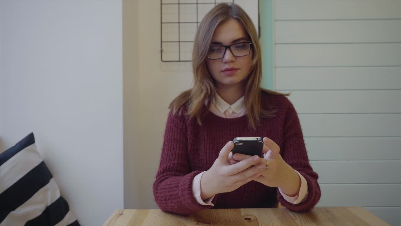 mujer joven usando un teléfono inteligente en un café