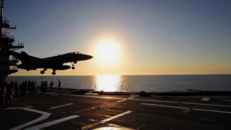 aircraft landing on an aircraft carrier at sunset