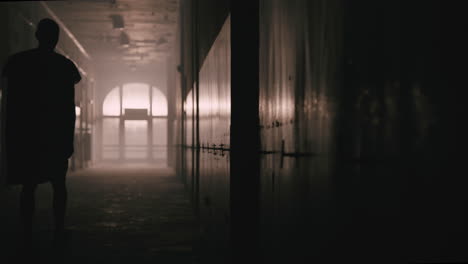 a bald man walks on the empty hospital corridor at night