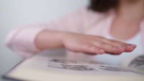 mujer toca suavemente la página del álbum de fotos en el interior. la señora muestra amor a los parientes fallecidos mirando las imágenes en el libro de familia. dulces recuerdos de la infancia pasada