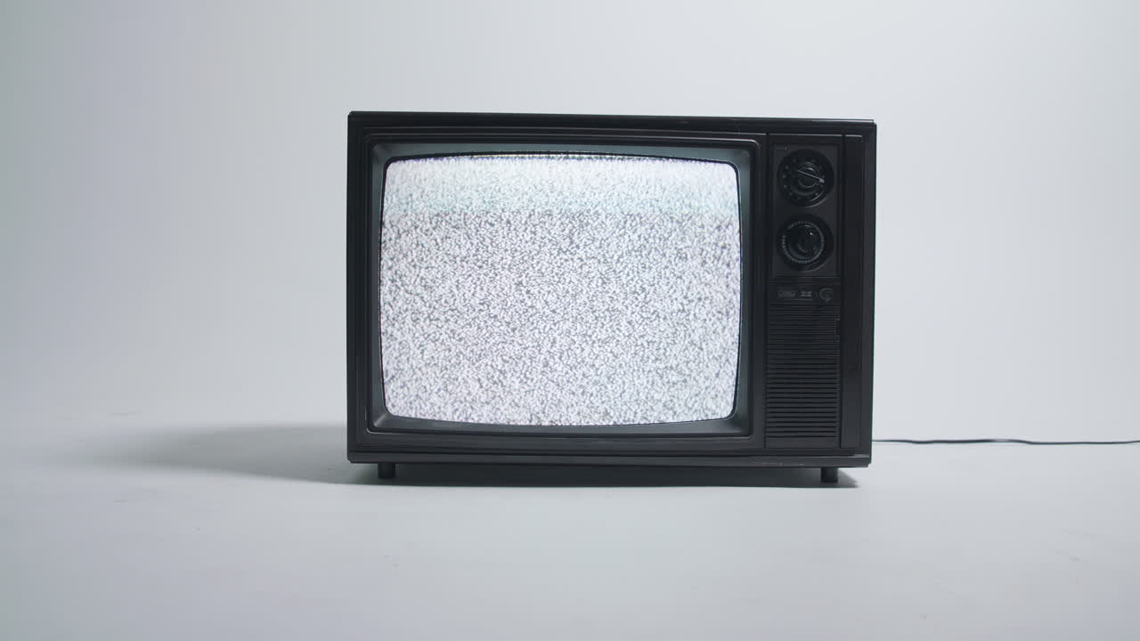 Televisore retrò che mostra rumore statico su una parete ciclorama bianca