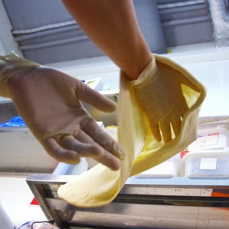 hands are forming dough for pizza on floured table and kneading it. chef is shaping floured dough for pizza. process of preparing pizza. close up
