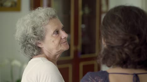 middle-aged daughter and mother talking on sofa, gesticulating