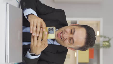 el video vertical del hombre trabajando desde casa disfruta de aplicaciones móviles en el teléfono.
