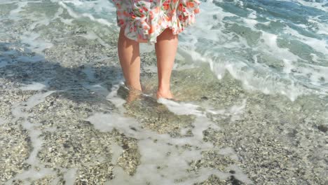 woman in summer dress walking into atlantic ocean barefoot, back view