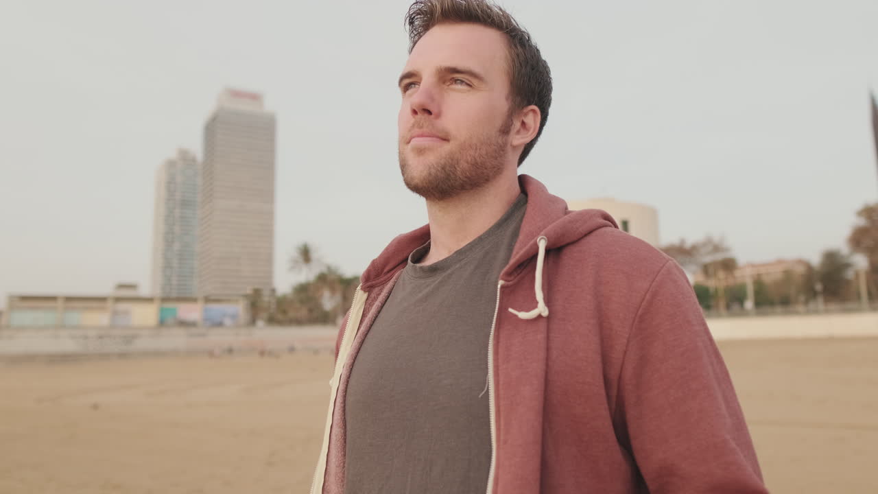 Man on a beach with a city in the background
