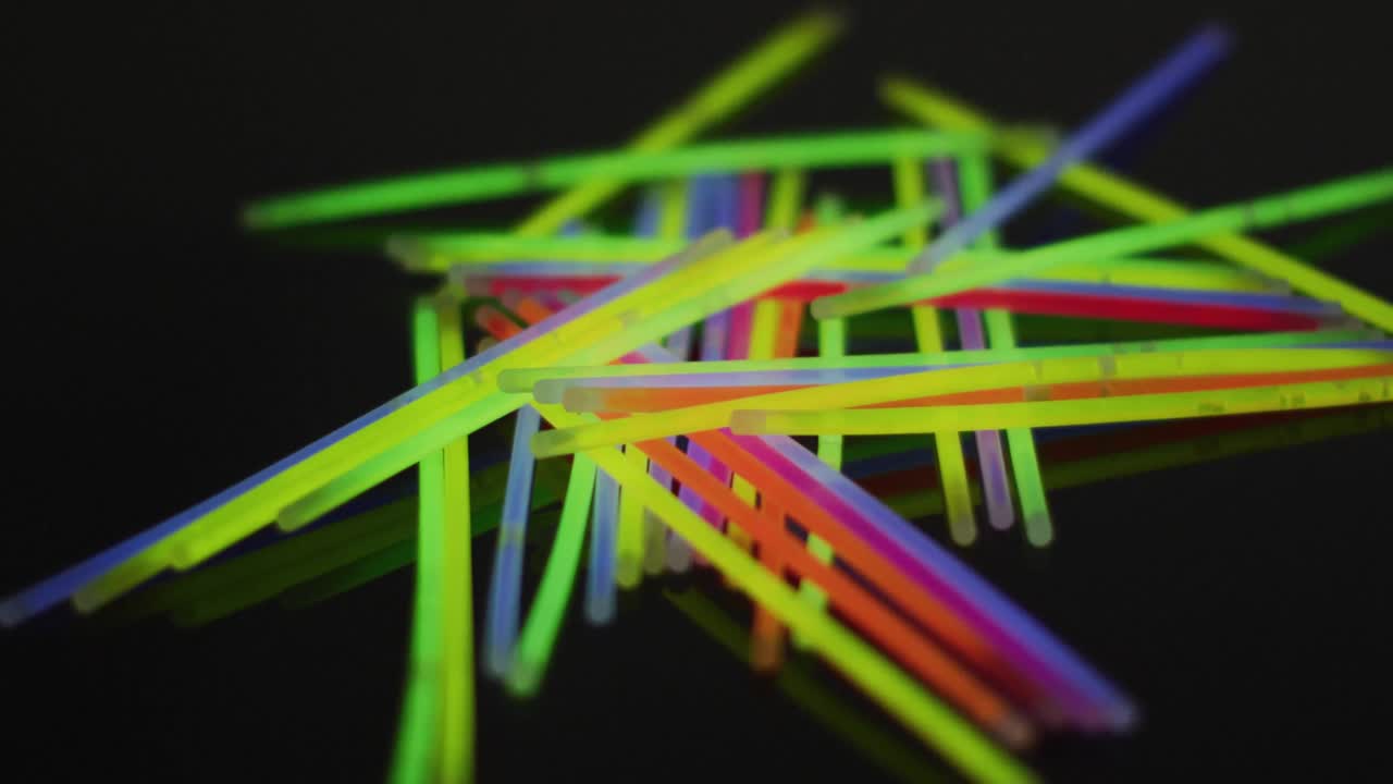 Animation of multiple colorful neon glow sticks over black background