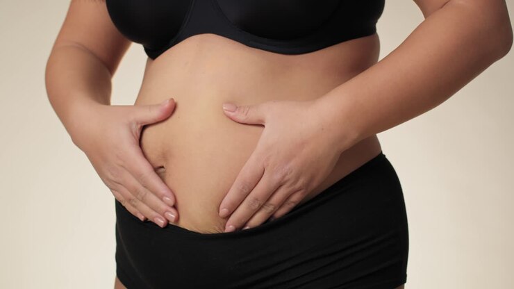 Unrecognizable plus size woman touching and pressing her belly.