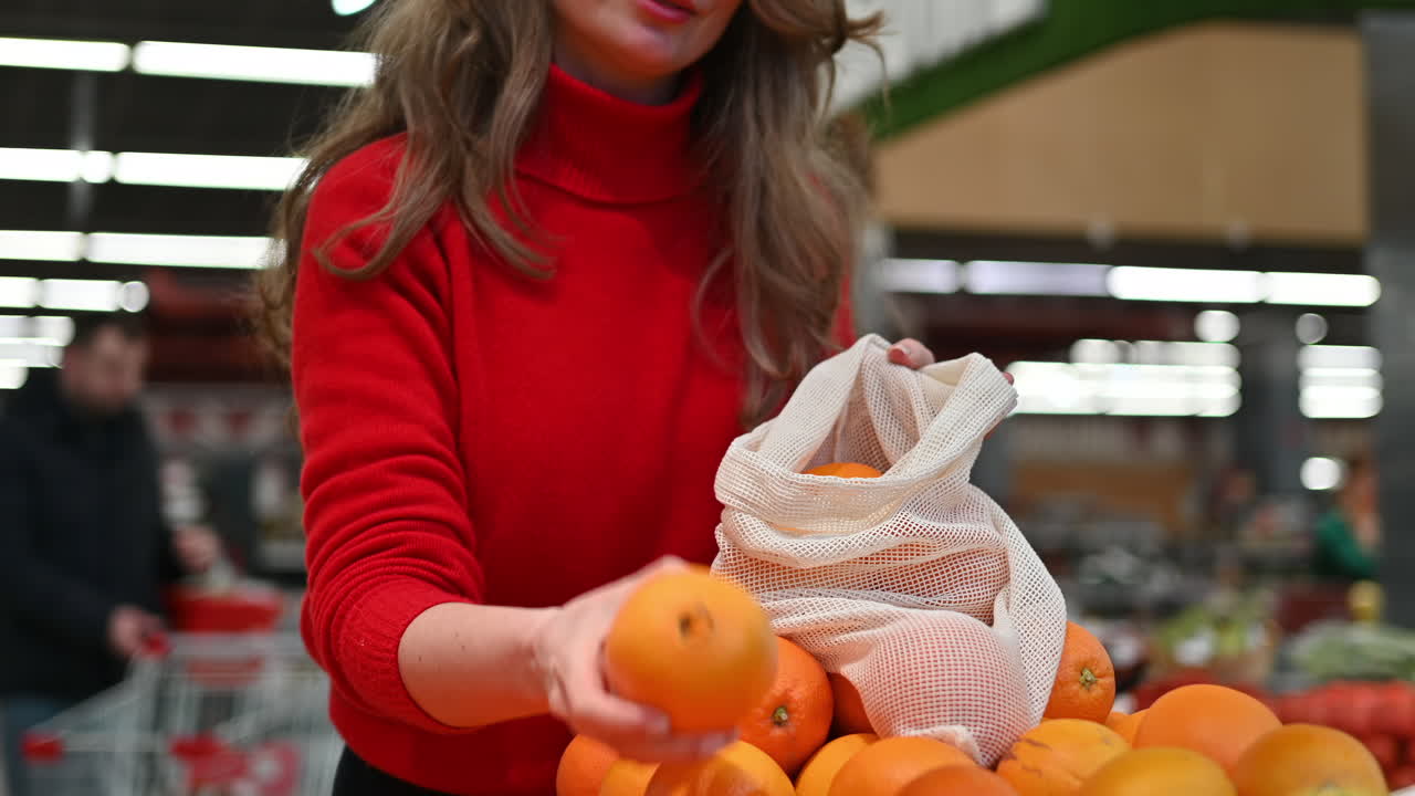 Donna che raccoglie arance in una borsa riutilizzabile in un negozio. Temi relativi all'ecologia e alla Giornata della Terra. Rallentatore