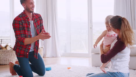 Young-white-couple-teaching-daughter-to-walk-at-home