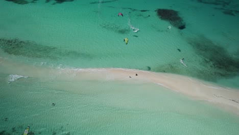 Kite-surfers-gliding-near-a-sandy-isthmus-in-cayo-de-agua,-aerial-view