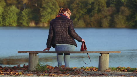 Young-girl-model-walks-up-and-sits-on-a-wooden-bench-with-lake-view