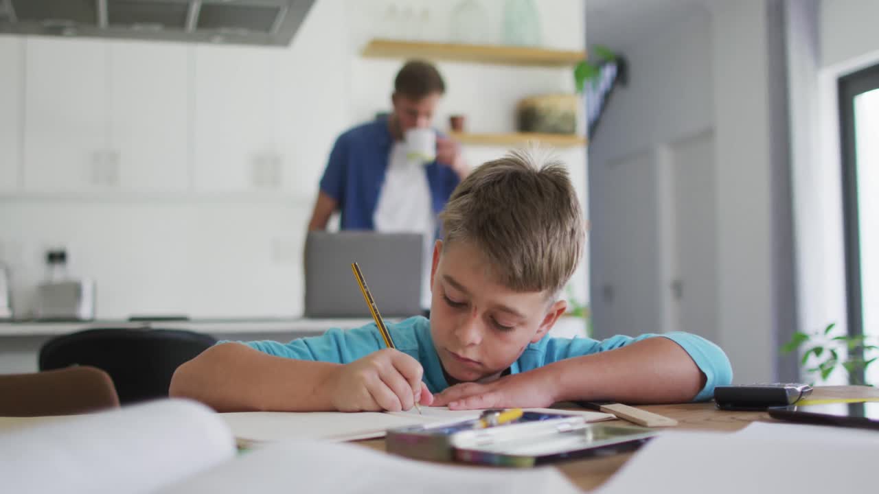 niño caucásico sentado en la mesa haciendo tareas escolares en casa
