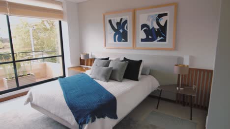 a panoramic view of a well-organized and clean home unveils a bedroom featuring a double bed, adorned with wall art, and abundant natural light, creating an inviting ambiance