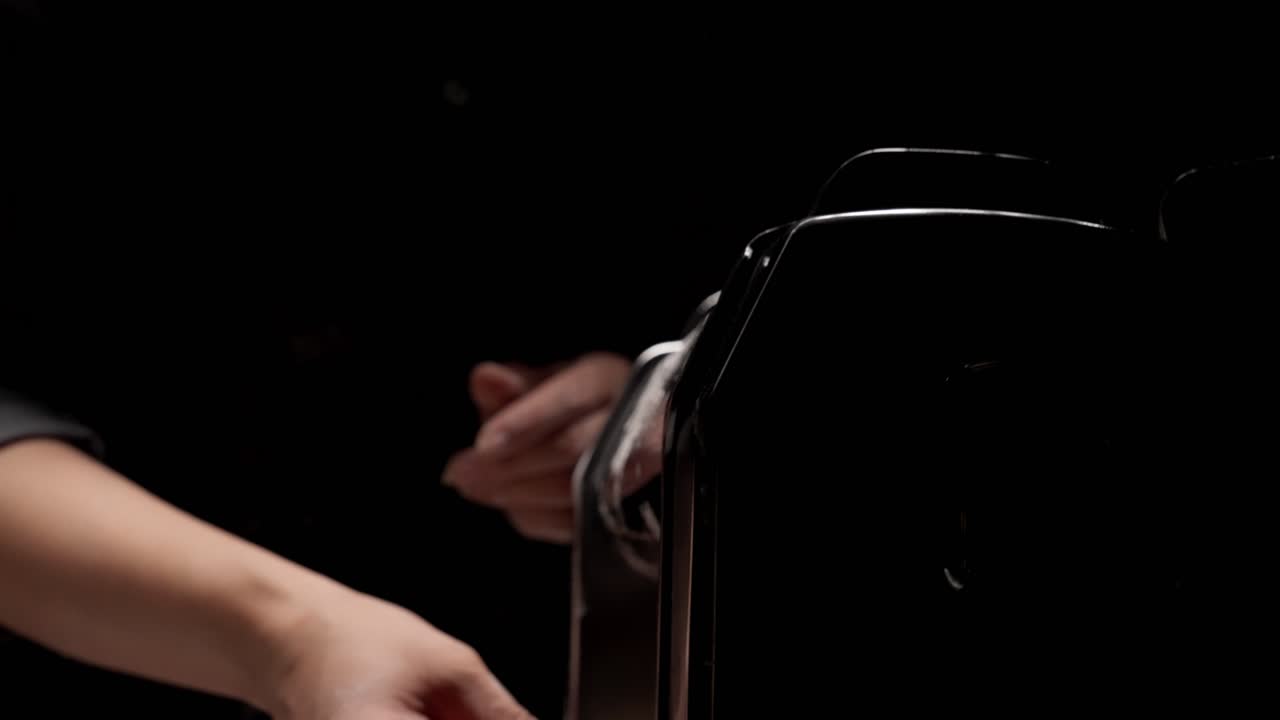 Primo piano di mani che preparano pasta fresca con una macchina per la pasta