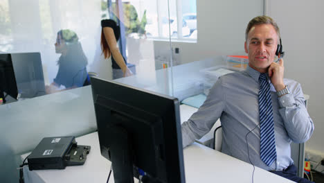 ejecutivo hablando con auriculares mientras trabaja en una computadora 4k