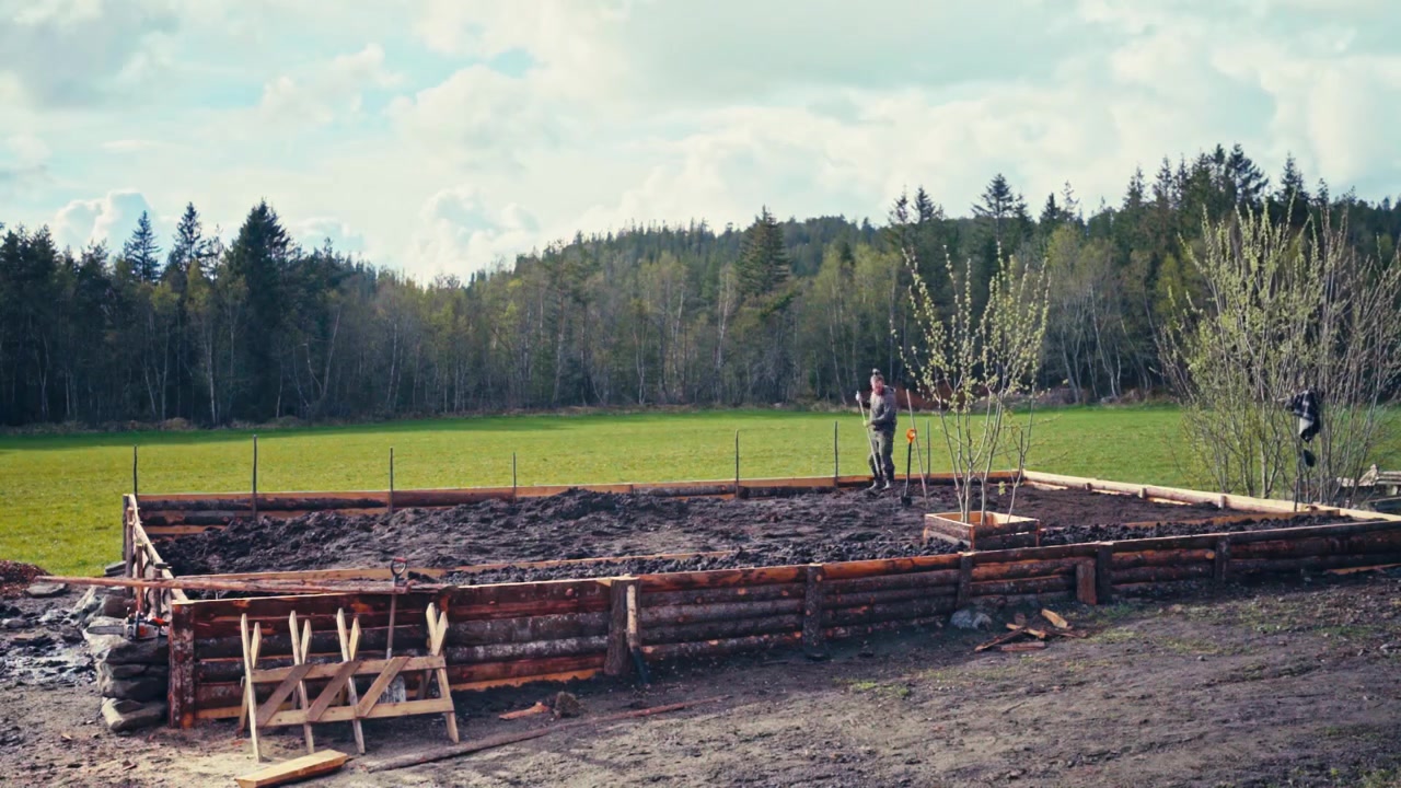 Man Is Working On DIY Huge Rustic Raised Garden Bed Enclosed By A Stacked Timber Log. Timelapse