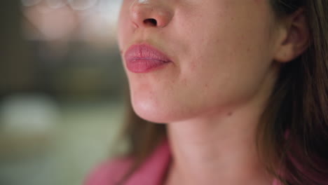 close-up of a woman in pink dress savoring a french fry with a soft smile, spots visible on her face, enjoying the delicious taste of the fry, with blurred colored lights in the background