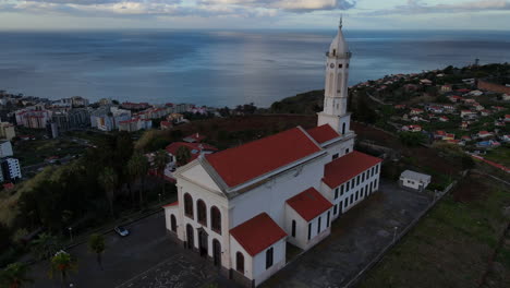 iglesia de sao martinho en madeira: vista aérea en órbita sobre la hermosa iglesia durante la puesta de sol y con vistas a la ciudad y el océano