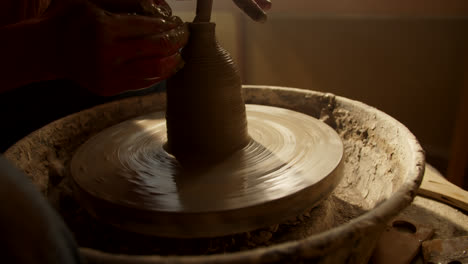 potter shaping a clay vessel on a pottery wheel