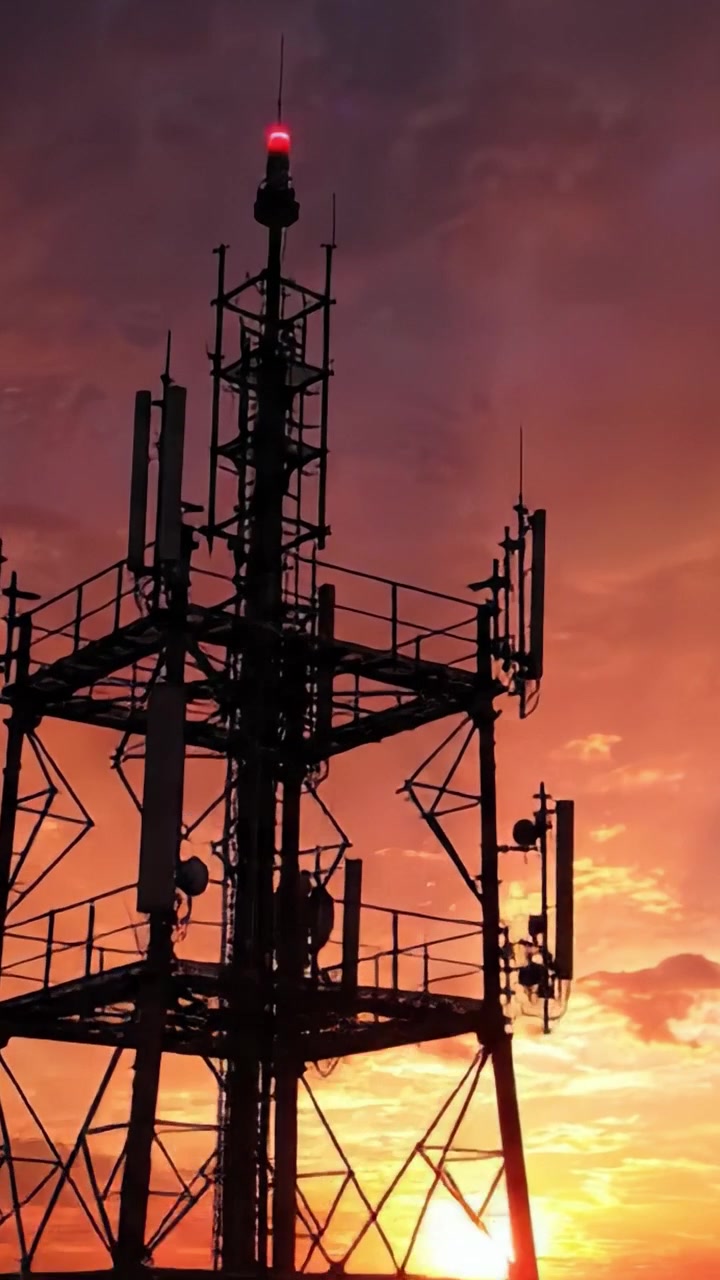Affascinante silhouette al tramonto di una torre di comunicazione tra nuvole vivaci e sfumature crepuscolari, che evidenzia la tecnologia moderna su uno sfondo naturale.