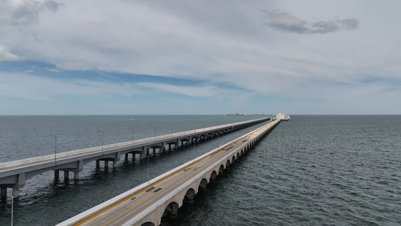 Aerial drone shot flying toward the long bridge that connects Progreso, Yucatán to the remote terminal. The drone approaches over open ocean, revealing the full length of the iconic pier
