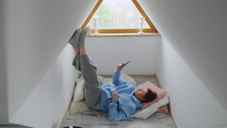 woman relaxing in attic room with phone