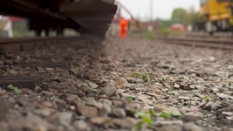 Nahaufnahme-Eines-Eisenbahnweichenhebels-Auf-Gleisen-Mit-Verschwommenen-Arbeitern-Im-Hintergrund,-Tagsüber