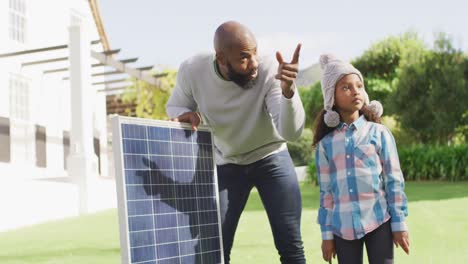 Video-Eines-Glücklichen-Afroamerikanischen-Vaters,-Der-Seiner-Tochter-Im-Sonnigen-Garten-Das-Solarpanel-Erklärt