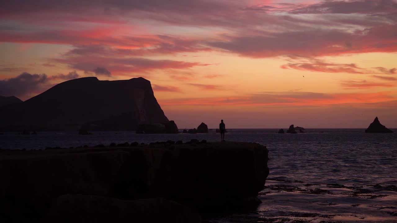 Silhouette landscape during dramatic colorful sunset at Peruvian coast, slowmo