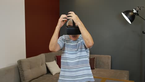 happy senior man using virtual reality headset glasses, trying to touch something, watching 3d video