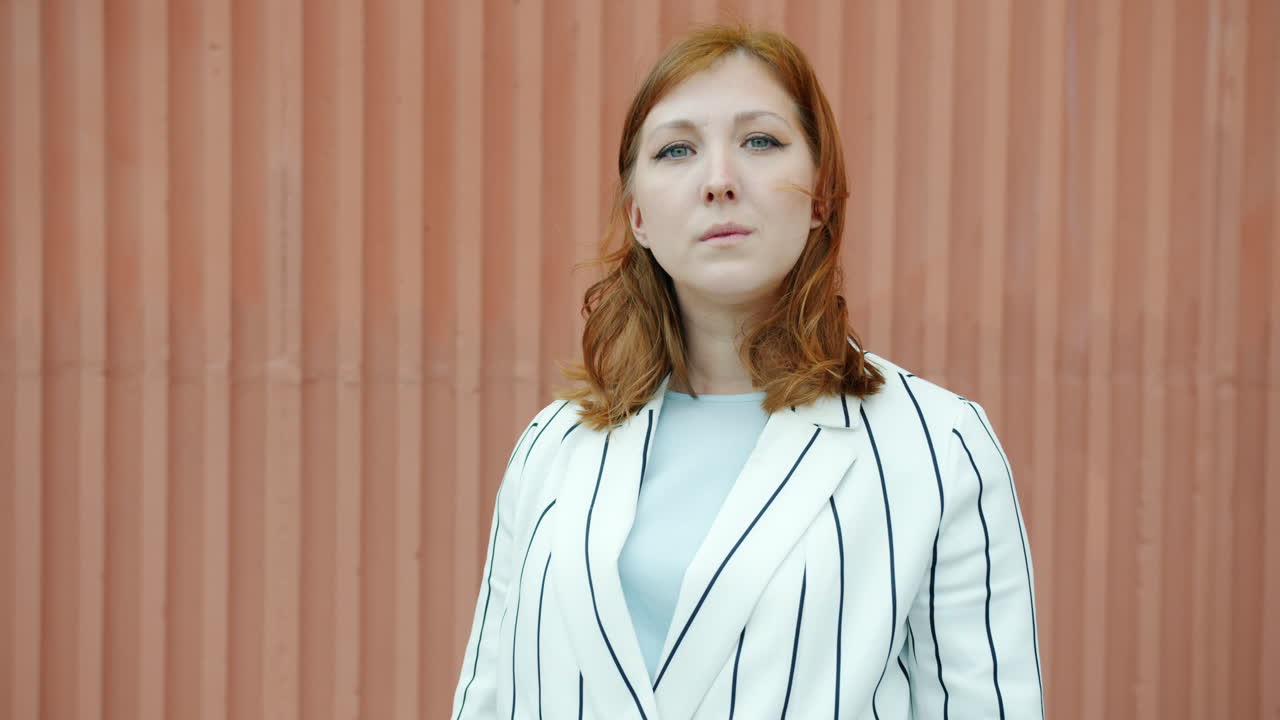 Woman waving and posing in front of a corrugated metal wall