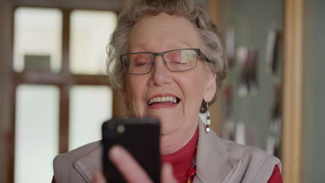 retrato de una mujer caucásica anciana feliz que usa un teléfono inteligente, envía mensajes de texto, navega, lee mensajes en una aplicación de teléfono móvil en un hogar de ancianos