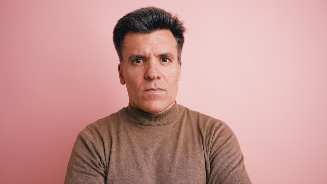 Close-Up Portrait of a Serious Man on Pink Background
