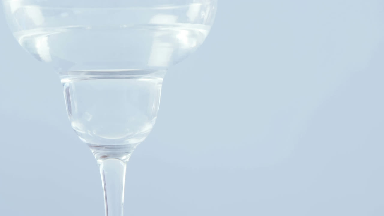 Abstract red decorative designs over olives falling into cocktail glass against grey background