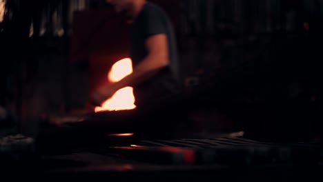 glowing iron with blacksmith working in background
