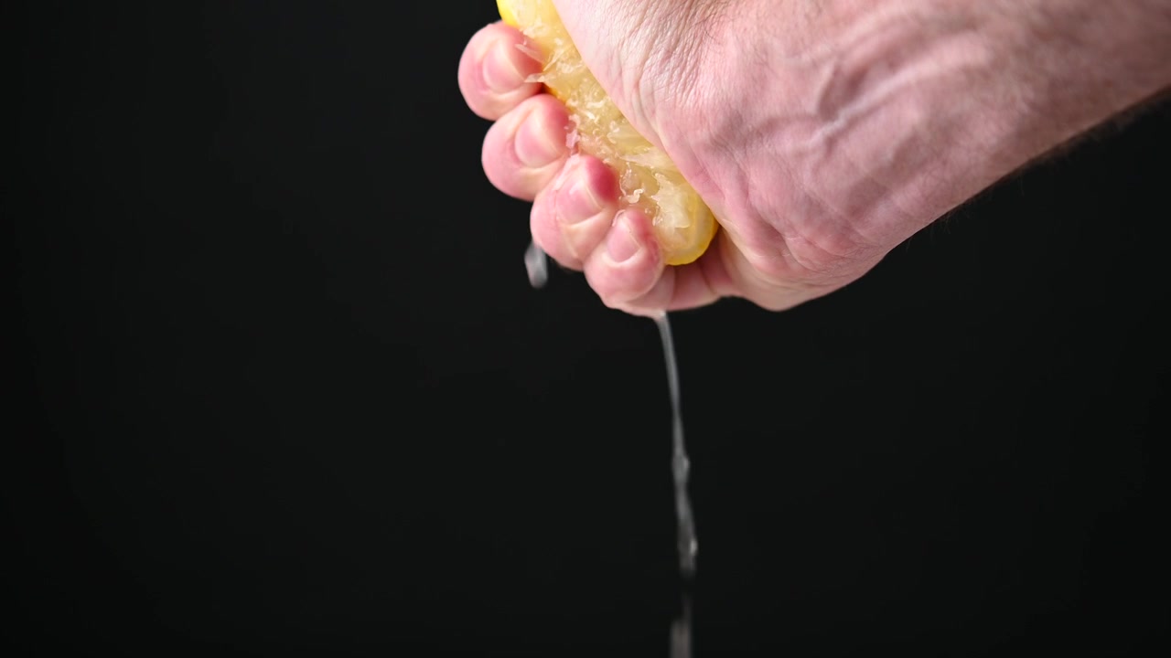 Mano che sprema un limone fresco.