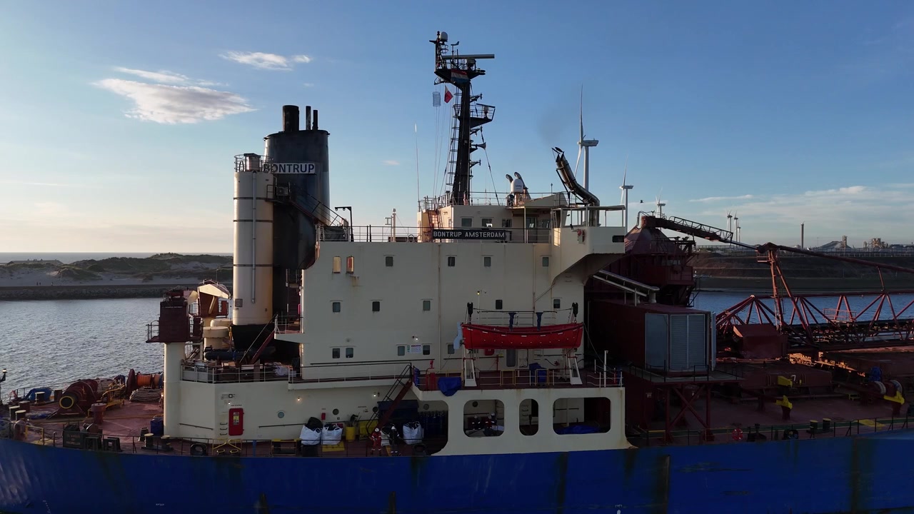 Static drone perspective as bulk carrier moves through frame