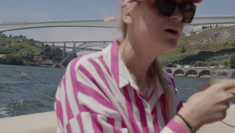 mujer disfrutando de una bebida en un barco con una vista del río douro y el puente en porto