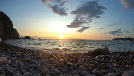 Lapso-De-Tiempo-De-Un-Amanecer-Detrás-De-Las-Nubes-En-Una-Playa-Empedrada-En-La-Costa-Brava,-Catalunya