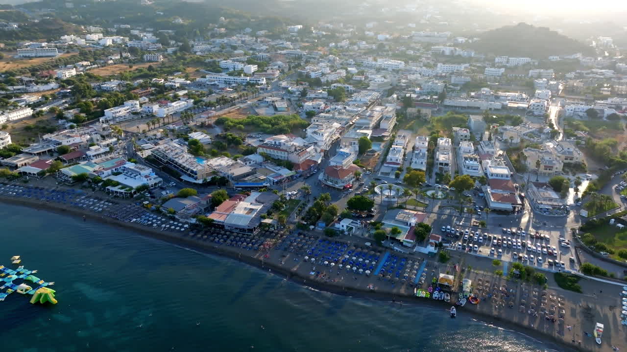 Aerial view circling the coastline of Faliraki village, sunny evening in Rhodes