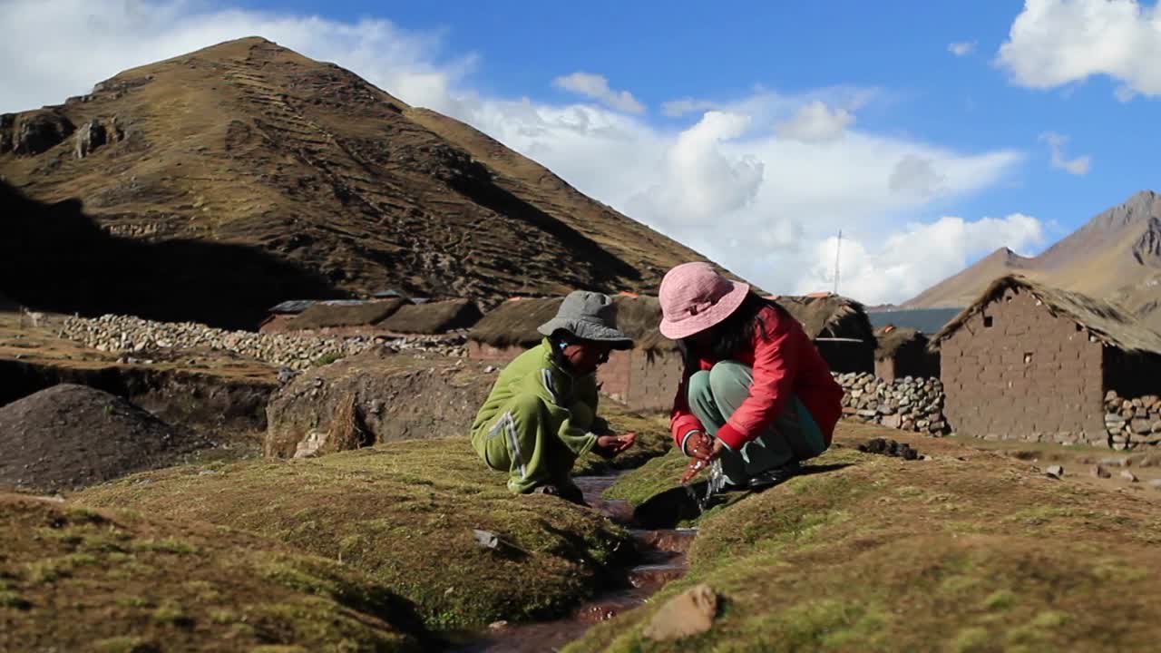 niños lavándose las manos en un arroyo burbujeante