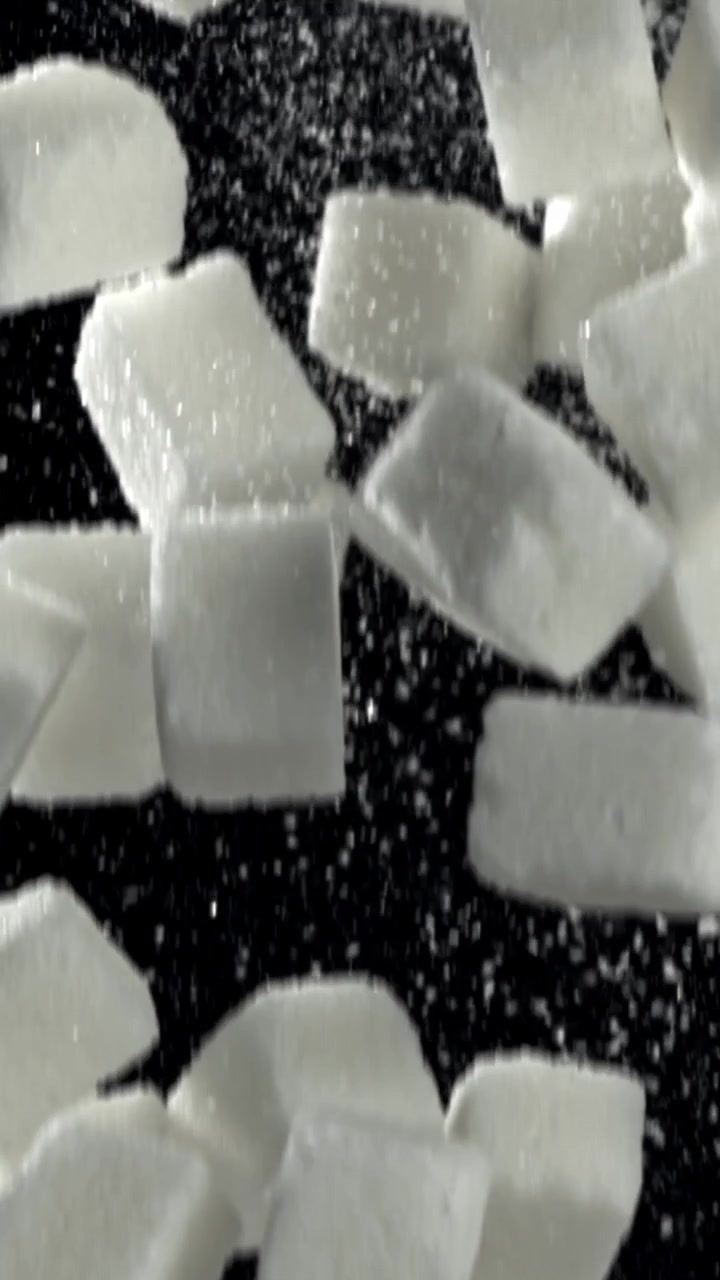 Hvide sukkerknalder falder i slowmotion på sort baggrund