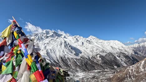 la cumbre del bajo kyanjin ri adornada con coloridas banderas de oración tibetanas, que simbolizan la paz y la compasión contra el telón de fondo de los majestuosos himalayas