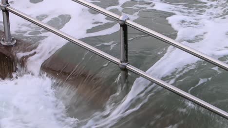 railings and steps being covered by a spring tide