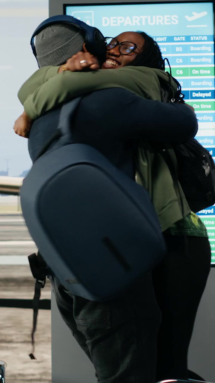 Video verticale: Scena emozionante in aeroporto con una coppia di colore che si abbraccia all'arrivo